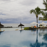 The backdrop of palm trees and an infinity pool overlooking sandy beaches.