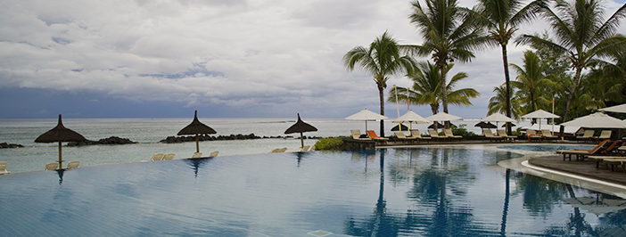 The backdrop of palm trees and an infinity pool overlooking sandy beaches.